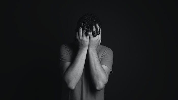 Black and white photo of a man holding his head at a drug and alcohol rehab in Weston-super-Mare