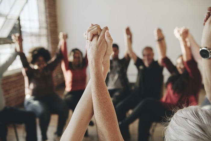 Group holding raised hands at a drug and alcohol rehab in Northamptonshire or near Northamptonshire