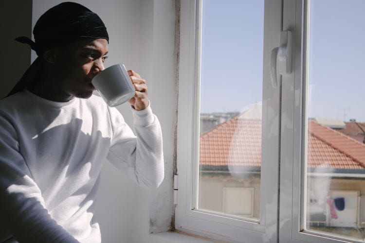 Man drinking coffee and looking out of a window at drug and alcohol rehab in Peterborough