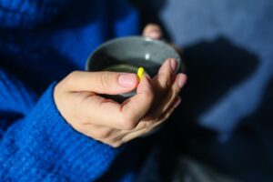 Someone taking medication holding a cup of tea