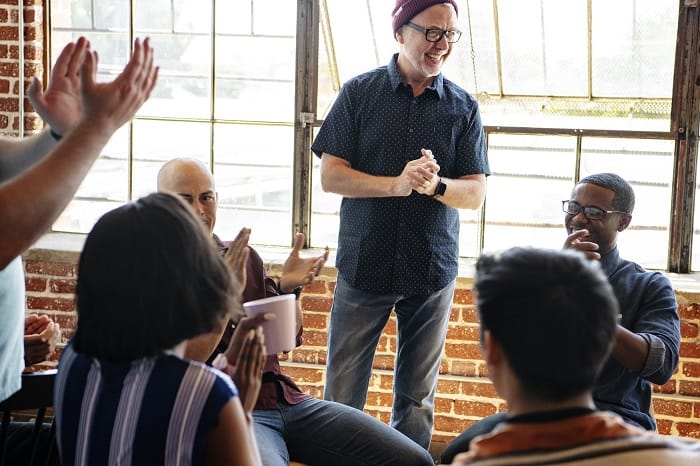 Support group smiling and clapping at a drug and alcohol rehab in Scotland