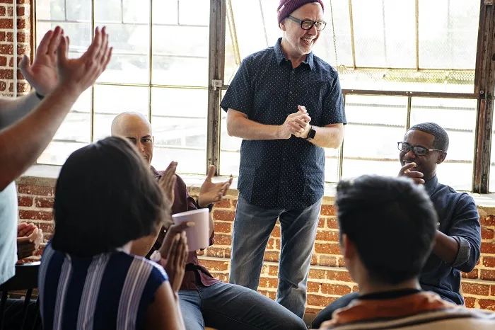 Therapy group smiling and clapping at a drug and alcohol rehab clinic in Reading