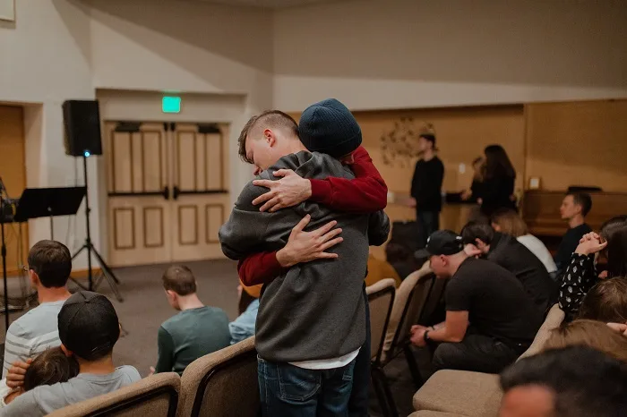 Two people hugging in a support group at a drug and alcohol rehab clinic in Devon