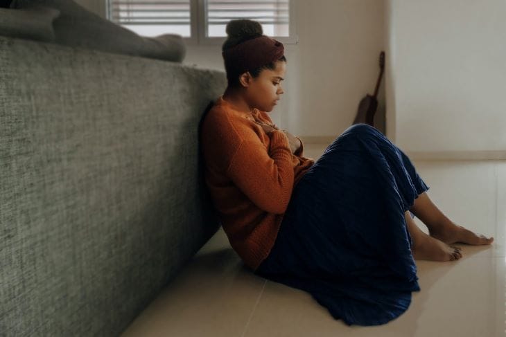 Woman sat behind a sofa looking concerned near Bolton