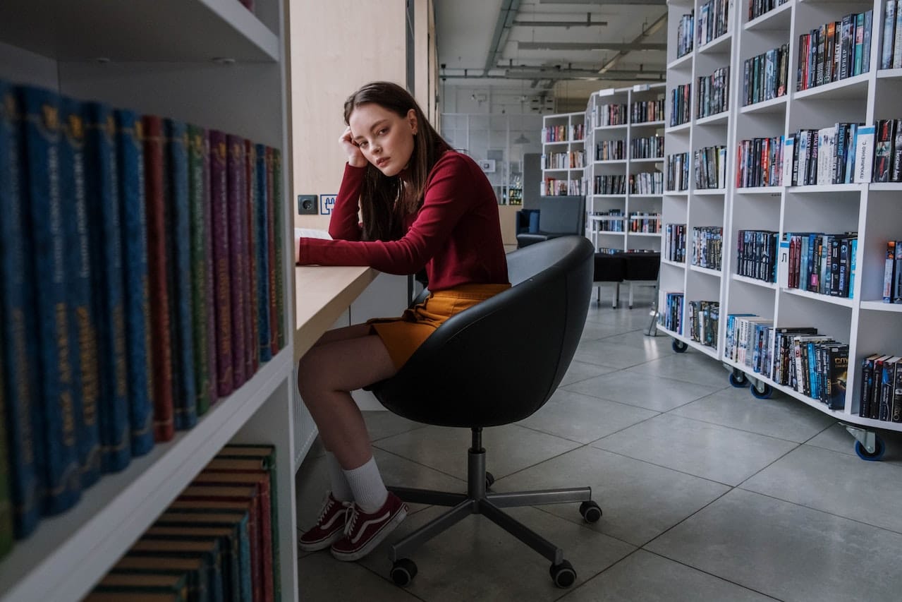 Woman sat in a library thinking about dehydration during Ramadan