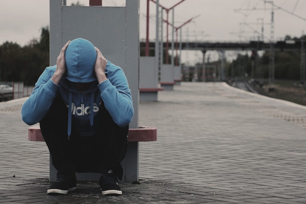 man with hood up in distress