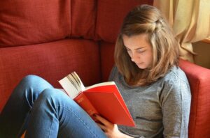 A woman reading a book sitting on a sofa