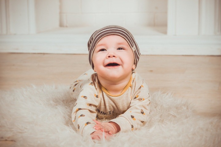 Photo of baby on rug smiling.