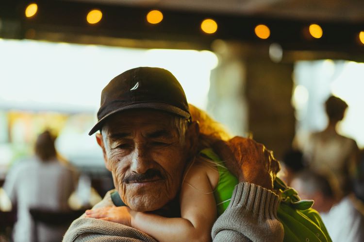 A man looking sombre while hugging his grandaughter