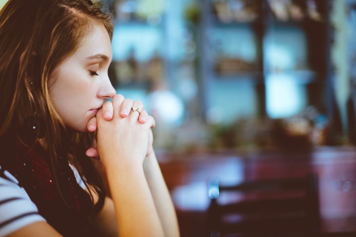 A woman with her eyes shut and hands clasped in a DBT therapy session at a Newcastle rehab