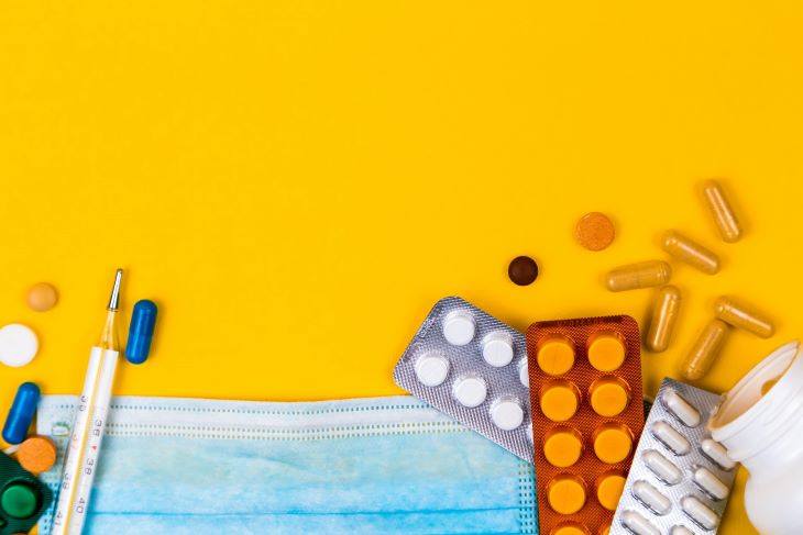 Pill packets and a mask on an orange background
