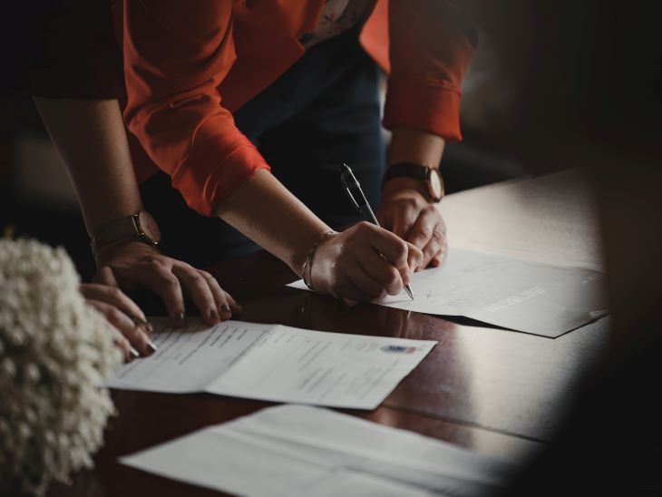 Two people signing paperwork