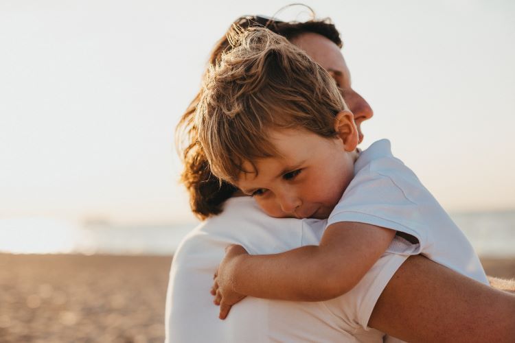 A mother holding her son at the beach