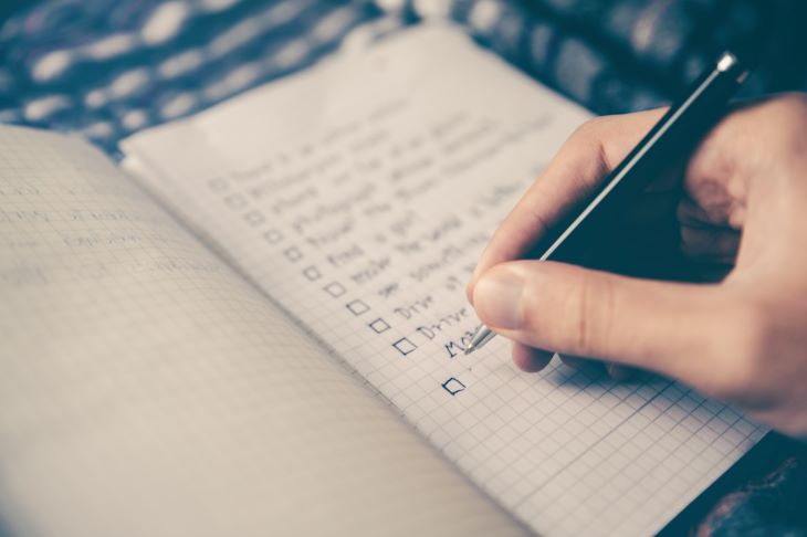A person writing a checklist in a notebook