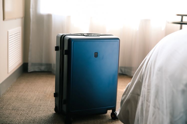 A blue suitcase by a bed
