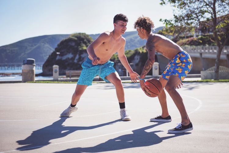 Two young men playing basketball in shorts and trainers on a sunny day at alcohol rehab Tunbridge Wells