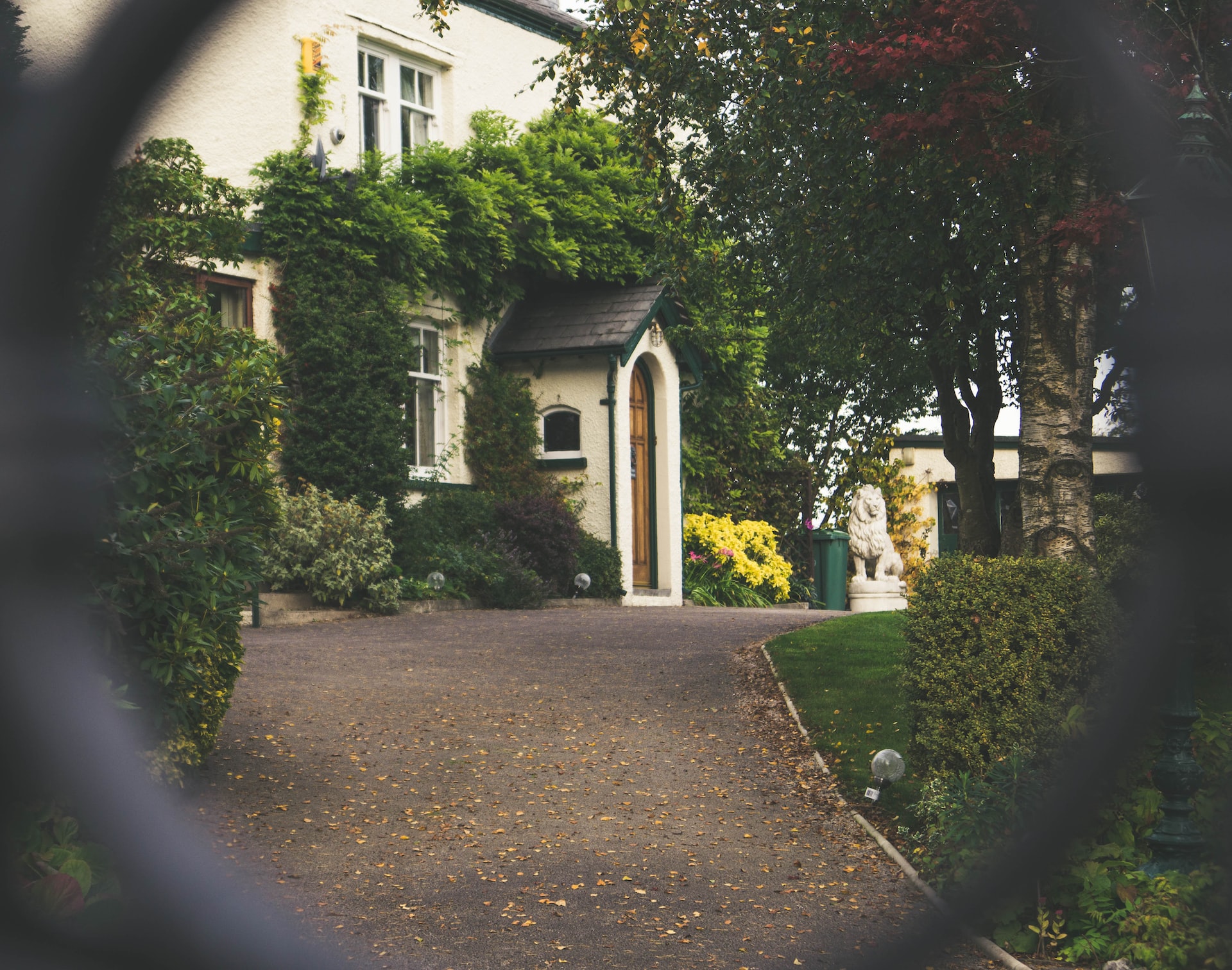 A large rehab house covered in greenery, seen between a gate supported by Aviva and Bupa