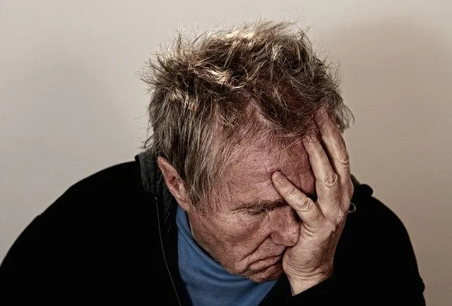 Older man holding his face and thinking about suicide
