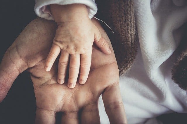 Infant hand resting on an adult hand