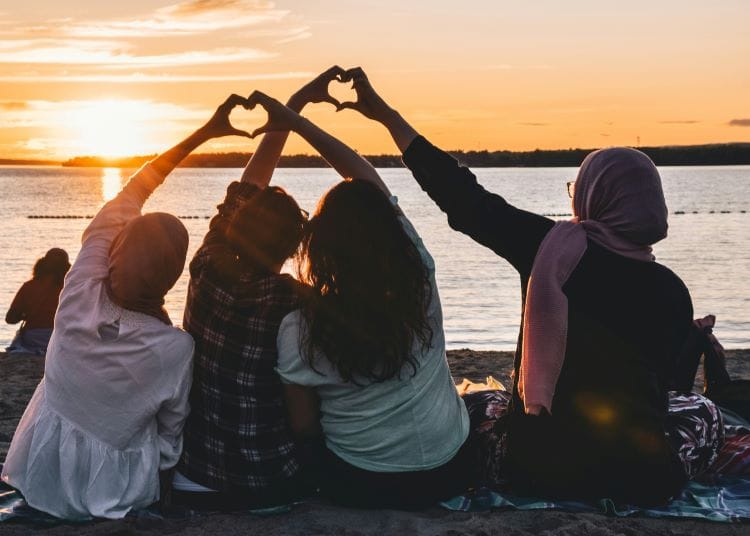 Muslim family making a heart shape with their hands at sunset