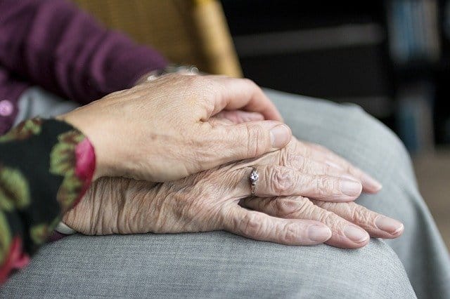Older woman and younger woman holding hands whilst talking about menopause and mental health