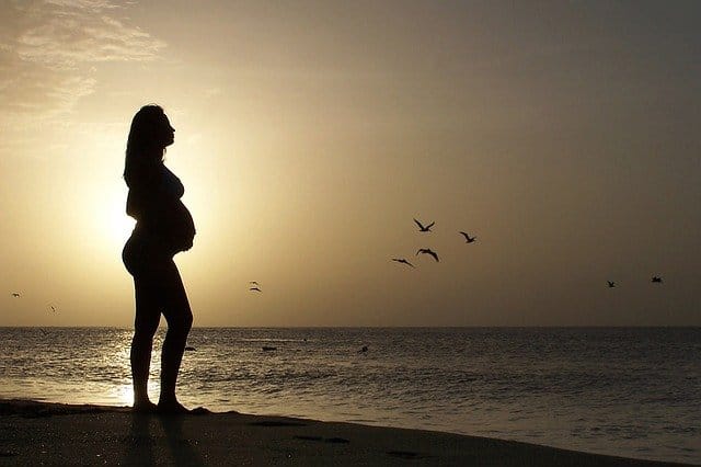 Pregnant person stood next to the sea contemplating heroin addiction