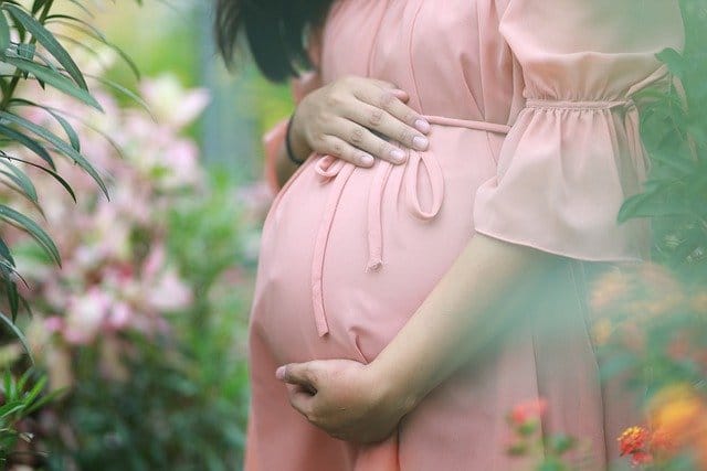 Pregnant woman stood in a garden contemplating heroin addiction