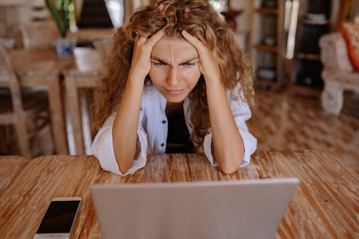 Woman looking tired and reading on a laptop about menopause and mental health