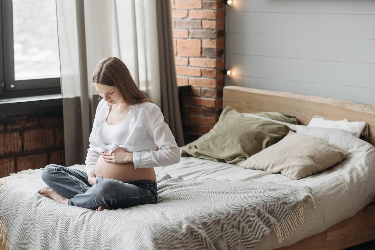 Woman sat on a bed thinking about pregnancy and heroin addiction