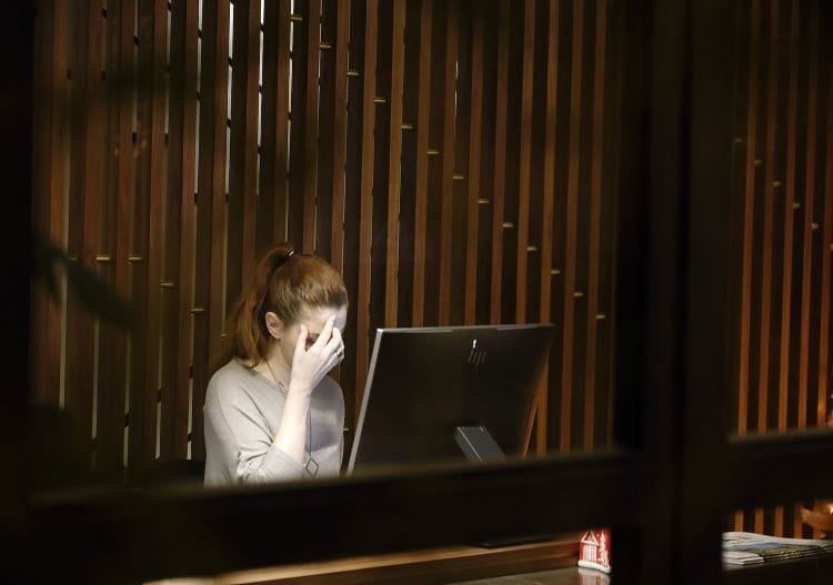 A woman with her hand over her face in worry