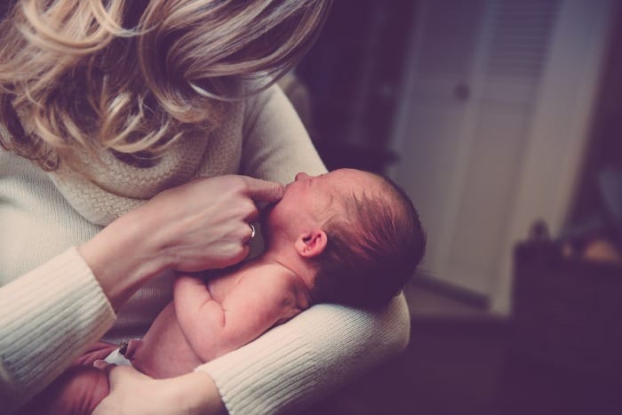 Woman holding a baby thinking about genetics and alcoholism