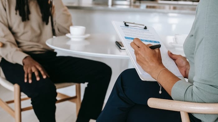 Addiction worker taking notes whilst speaking with a patient about how much rehab costs in the UK