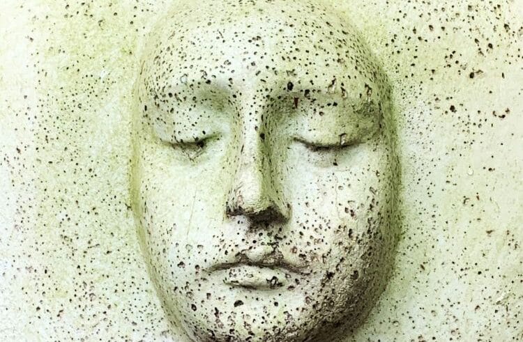 A sculpture of a white face that has been dented