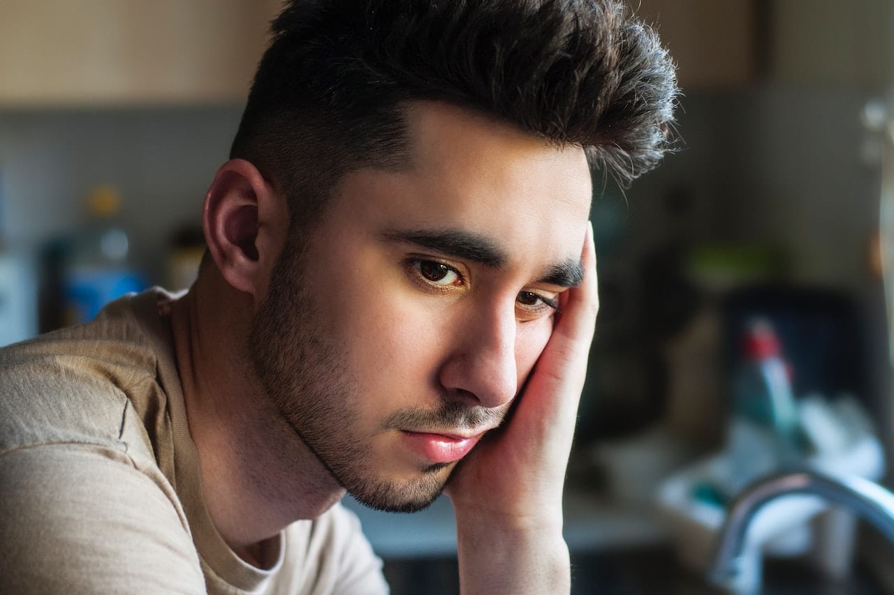 Young man looking sad thinking about underage drinking and its health impacts