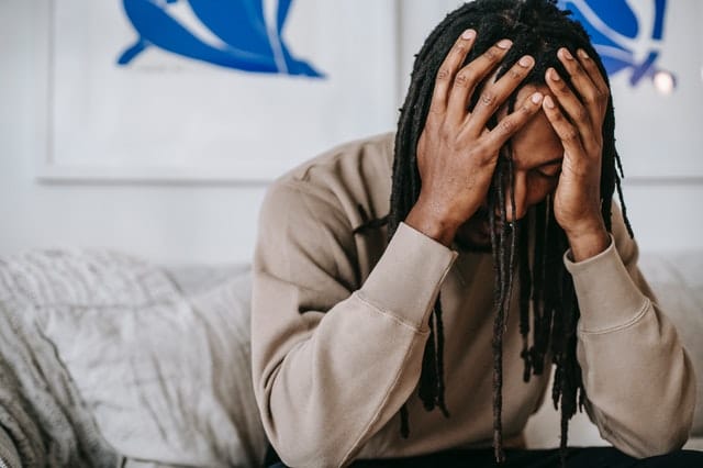 Man holding his head and suffering from alcohol withdrawals after quitting alcohol suddenly