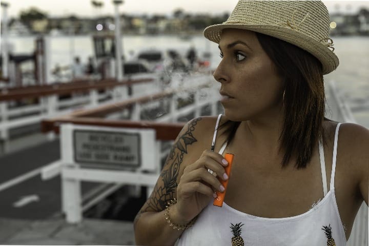 Woman holding an e-cigarette and thinking about vaping addiction