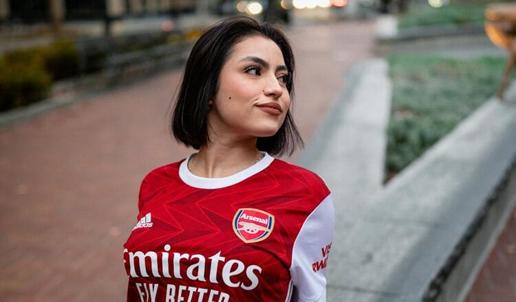 A sober woman in a football shirt smiling and looking to the side