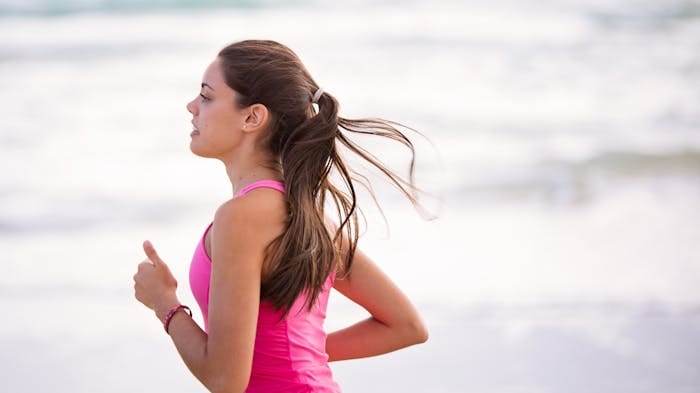 Woman running on a beach engaging in exercise for anxiety