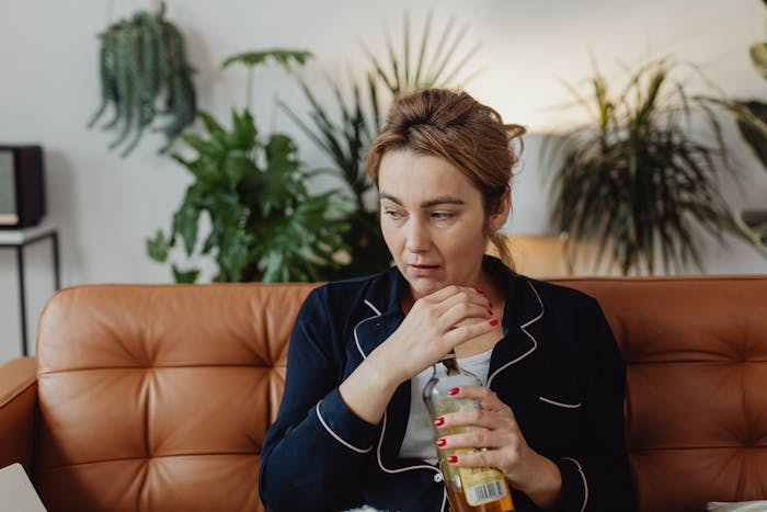 Woman sits with alcohol bottle