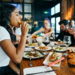 A table of people at a restaurant, smiling and eating